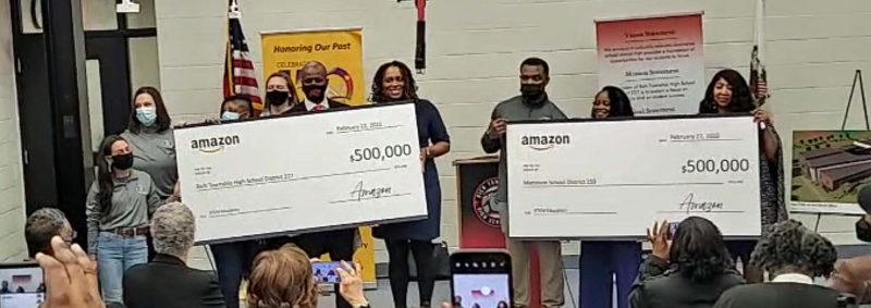 group photo of school officials accepting oversized checks from Amazon