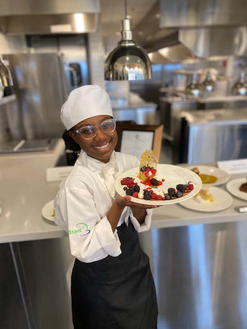 young man in chefs outfit holding plate