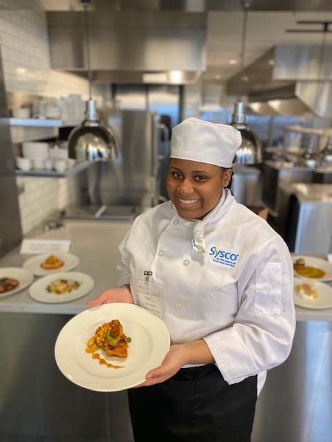 younf woman in chefs outfit holding plate