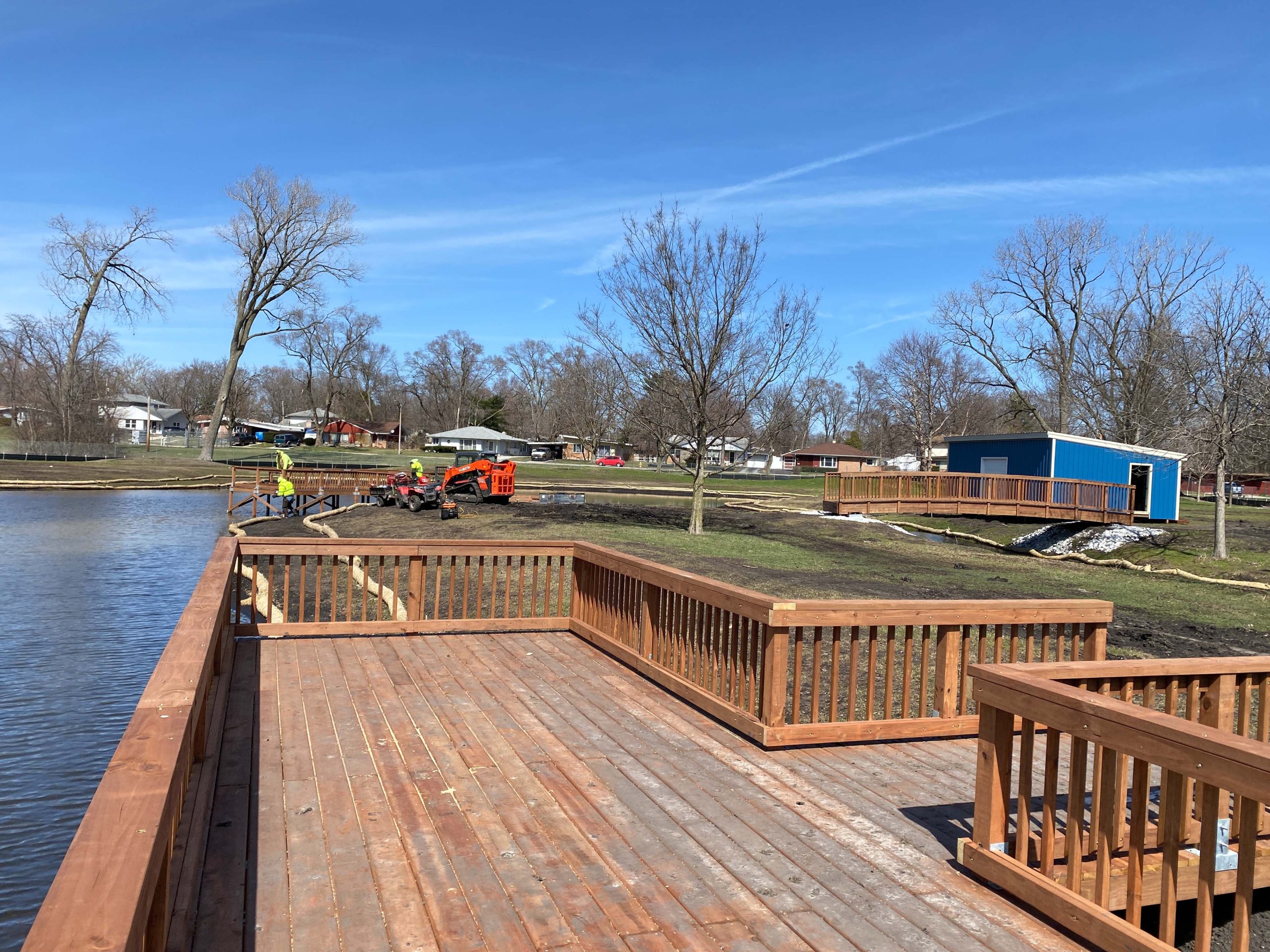 Wooden fishing pier extending into water, Blue building in teh background.