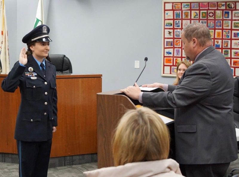 police officer raises hand as she is sworn into office by village manager