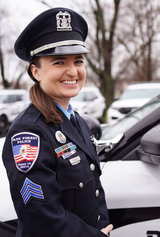 femaile police officer in uniform standing in front of cars