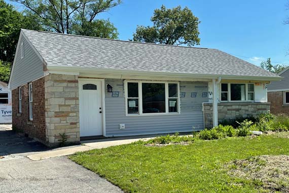 brick and siding house under final rehab with green grass in front