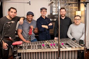 group of five men standing behind a xylophone
