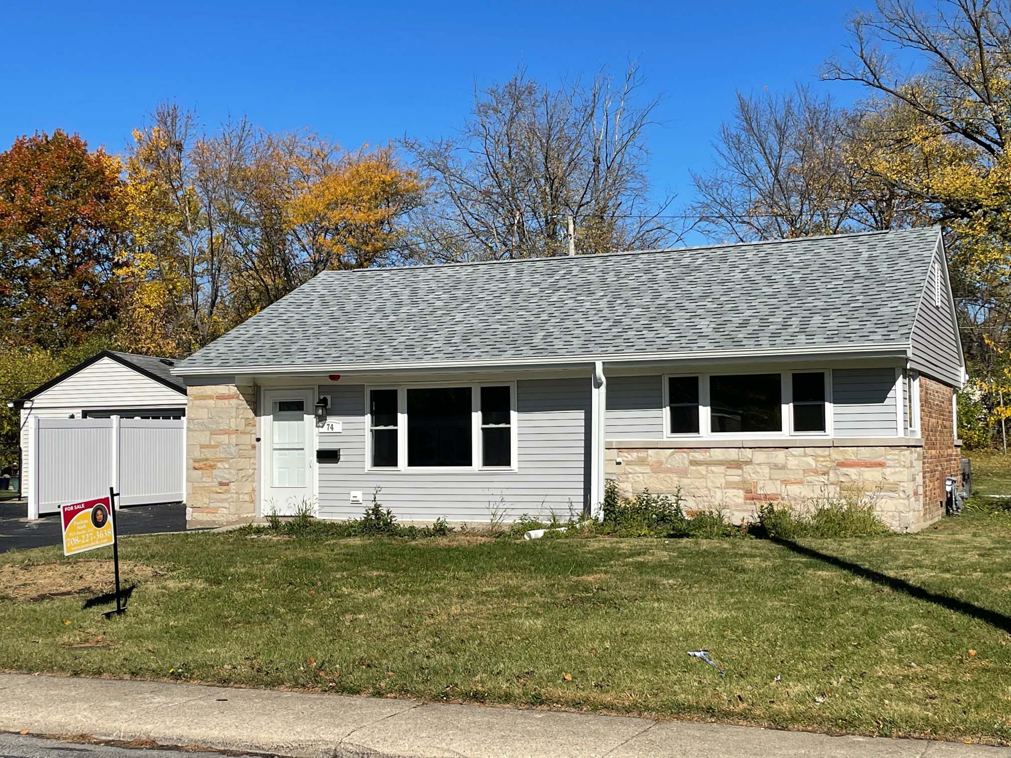 grey house with a for sale sign in front