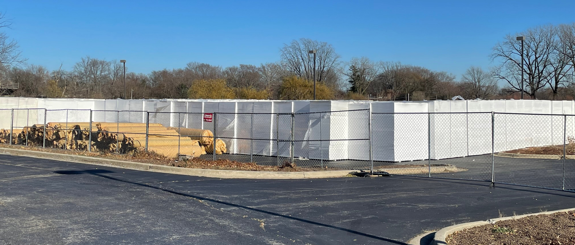 Fence around stockpile of building material in a parking lot