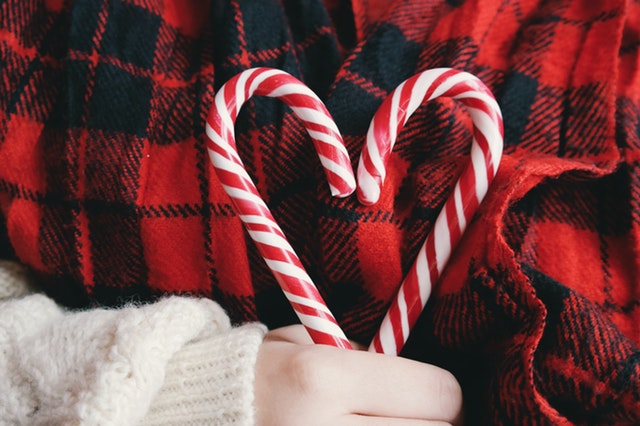 image of a person dressed in red plaid holding two candy canes together to form a heart