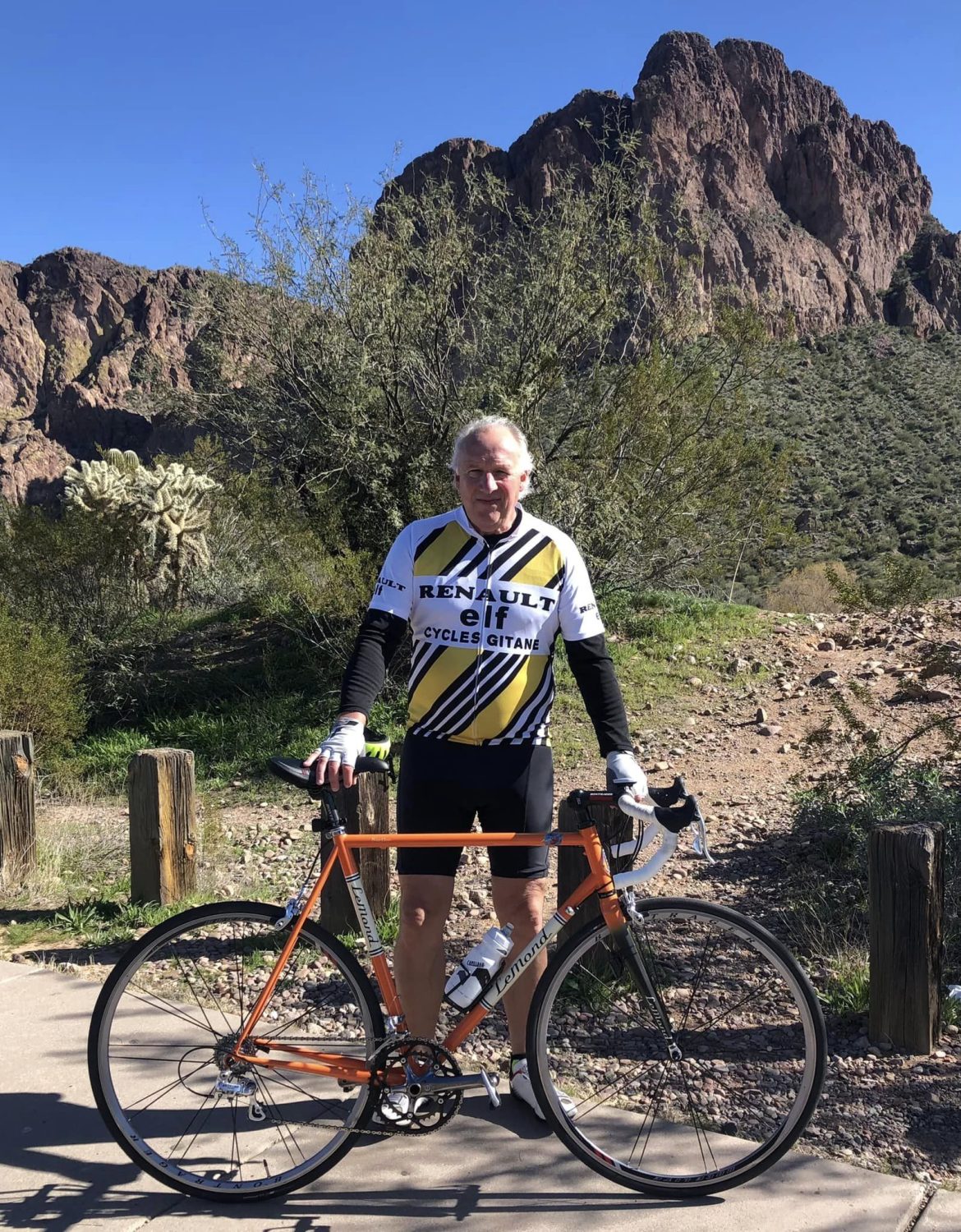 man in bicycle riding outfit standing behind his bike