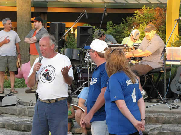Man with microphone speaking to an outdoor gathering