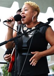 woman singing on stage into a hand-held microphone