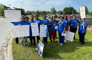 group of people wearing blue shirts and holding signs pose for a group picture