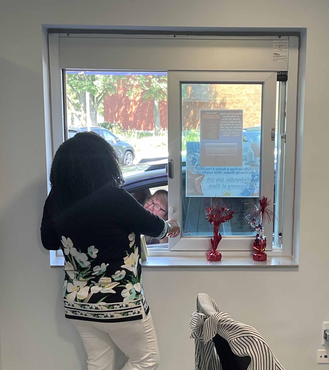 woman on the inside of a drive-up window talking to a woman on the outside of the window sitting in a car (Photo John Hudzik)