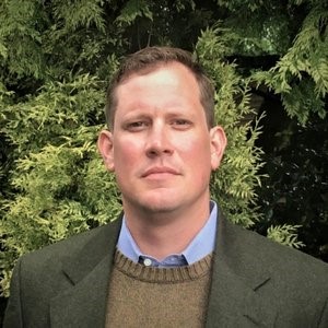 portrait of man wearing suit with trees in the background