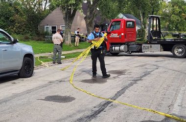 A Park Forest officer gathers crime tape while other local and State Police discuss the incident. (Gary Kopycinski)