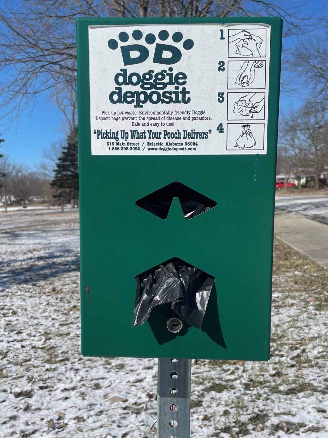 metal rectangular dispenser of dog excrement bags in a park setting