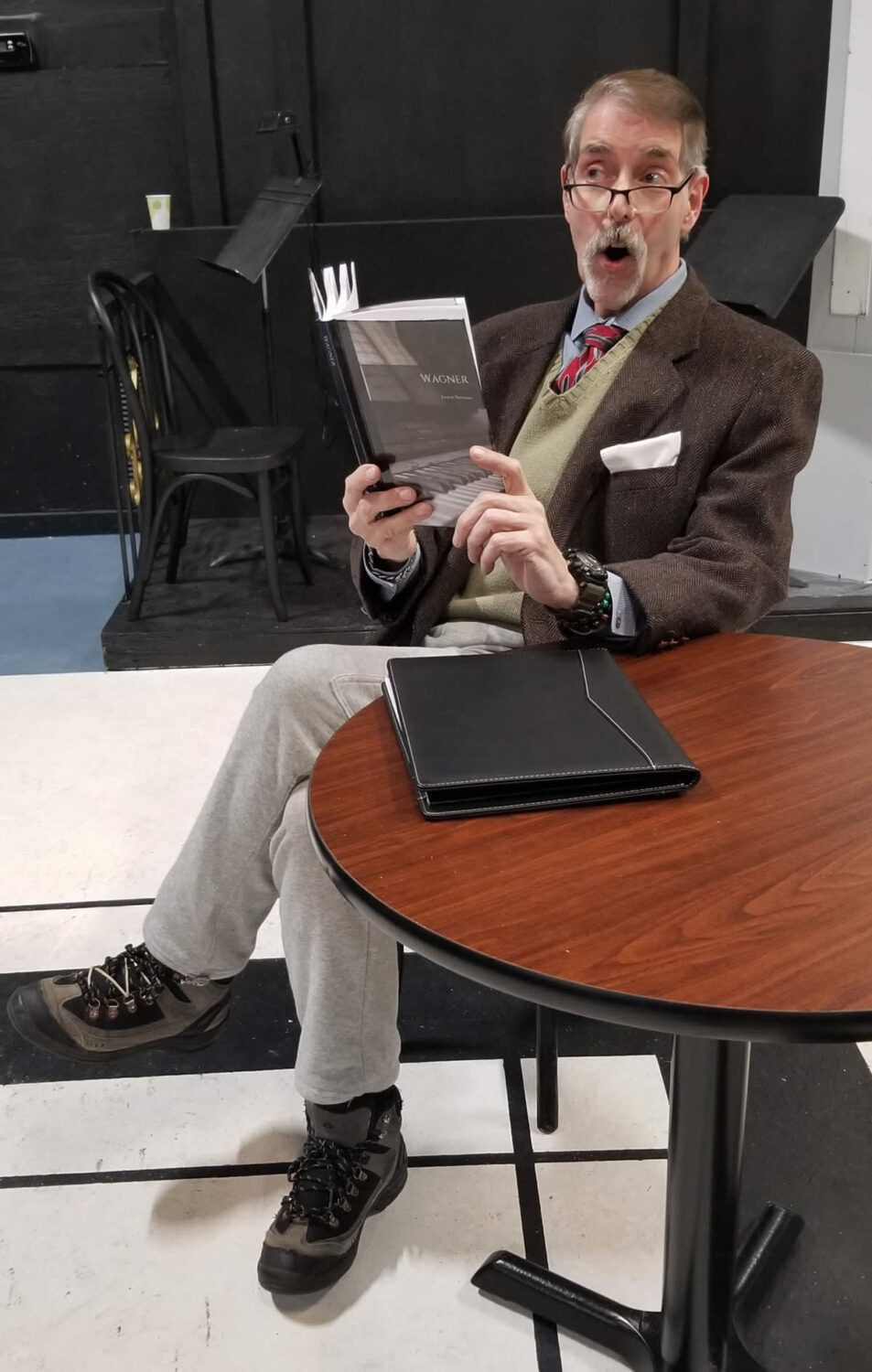 Reggie (Mike Cabsinger) realizes “Newmann was right!” while reading. The comedy Quartet runs at The Drama Group from April 12 to 21.