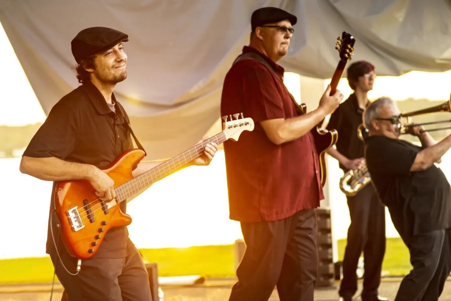 group of four musicians, two with guitars, one with trombone and one with saxophone