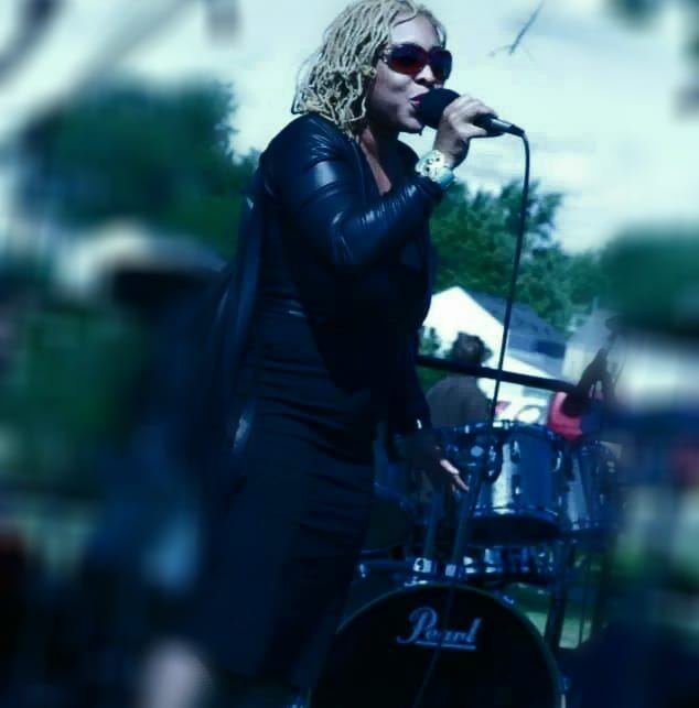 woman wearing sunglasses sings while holding microphone