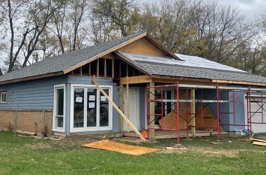 house being renovated with plywood on lawn and scaffolding in front