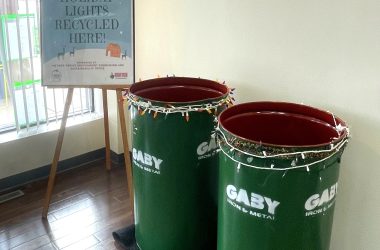 a sign on an easel stands next to two recycling bins
